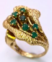 A Vintage 18K Gold (tested) and Emerald Forest Ring. Seven green emerald blossoms sit amongst