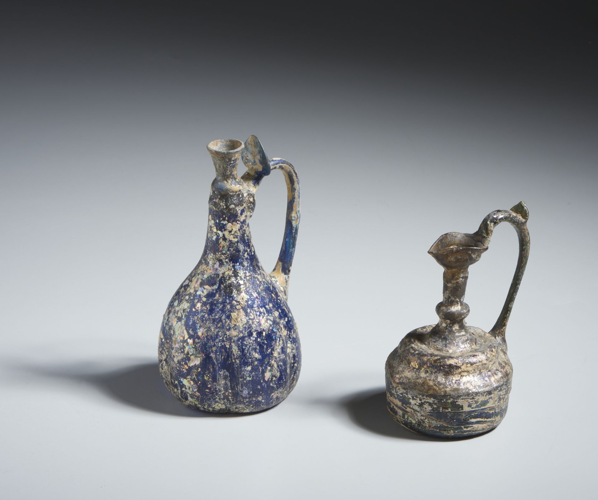 Two glass ewers Persia or Syria, 10th-12th century Cm 9,00 x 17,50