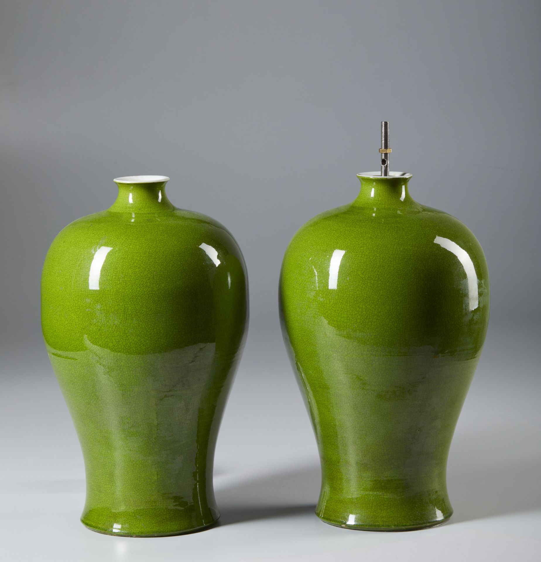 A pair of green glazed porcelain meiping vases bearing a Kangxi six charcater mark at the base