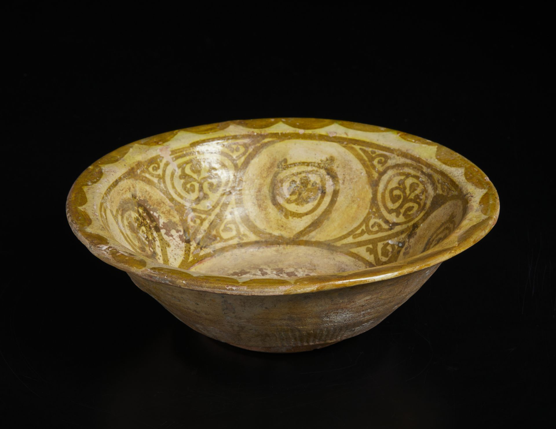 A terracotta bowl with olive green floral decoration Iran, 10th century or later Decorated imitating