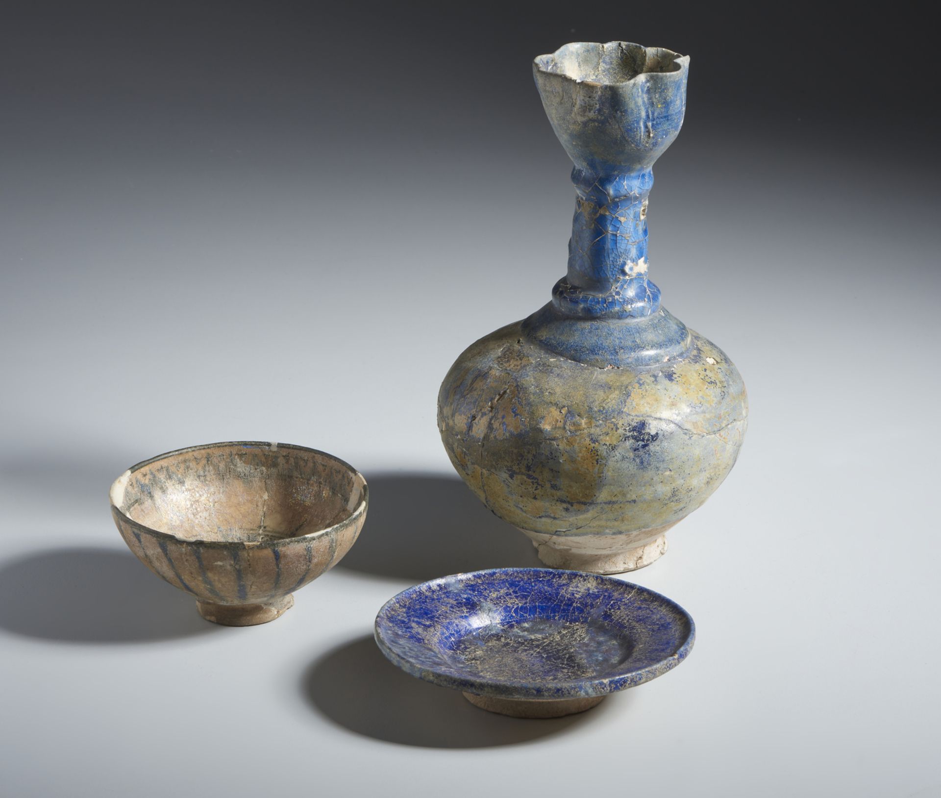 A group of 3 blue pottery vessels Iran, 13th century Fritbody, including: a moulded bottle covered