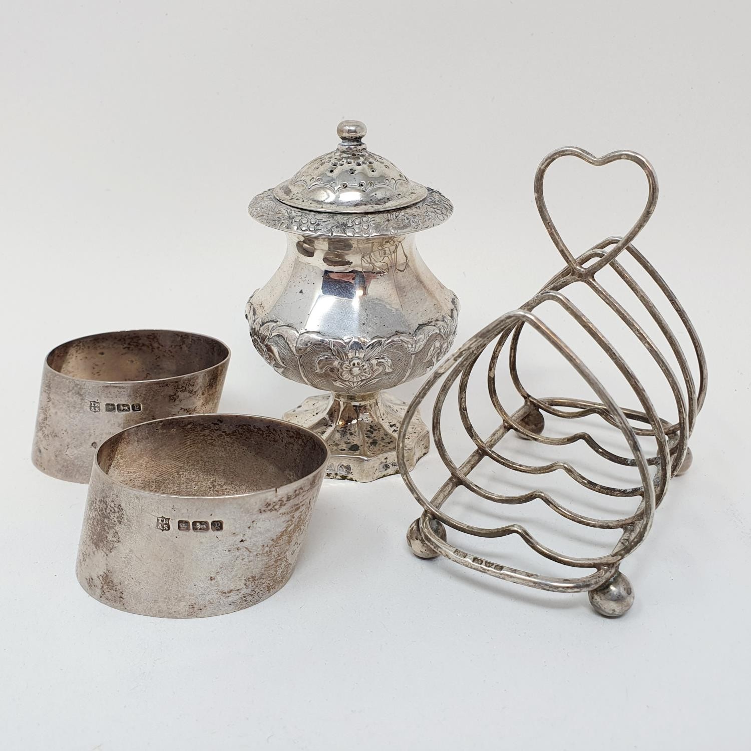 A Indian silver coloured metal pepperette, a four division toast rack, and a set of napkin rings, - Image 2 of 3