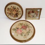 A needlework of roses, 26 cm diameter, another, 33 cm diameter, and a panel of roses, 23 x 17 cm (3)