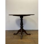 An oak oval tripod table, on a column support to scroll feet