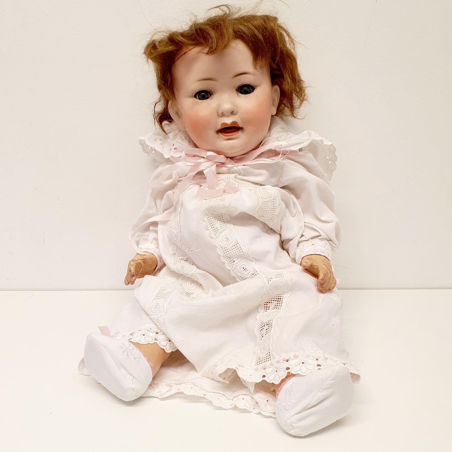 A German bisque headed doll, makers mark PM No 914, with a composite body and millefiori glass