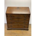 A George III oak bureau, the fall front to reveal a fitted interior, above four graduated drawers,