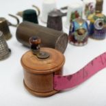 A miniature tape measure, in the style of a fishing reel, and assorted thimbles (qty)