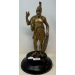 A brass figure of a Roman centurion, 30 cm high, on a later ebonised base Some wear to the figure,