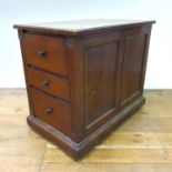 An early 20th century oak desk side cabinet, with a tooled leather top and three drawers, 77 cm high