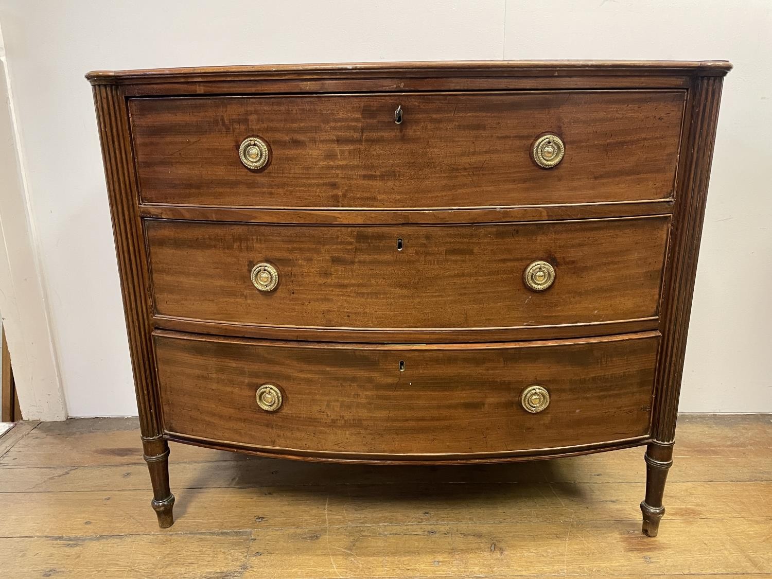 A George III mahogany bow front chest, of three drawers, flanked by reeded column supports, 88 cm