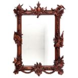 A large carved mahogany mirror, decorated assorted heraldic motifs, 136 x 94 cm Some small losses,