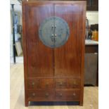 A Chinese hardwood cupboard, with two doors, above six drawers, inset with engraved metal plaque,