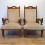 A pair of early 20th century Arts & Crafts style walnut armchairs, with padded backs, arms and seat,