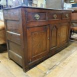 An oak dresser base, having three drawers and two cupboard doors, 140 cm wide Variation of colour,