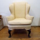 A George III style wingback armchair, on mahogany cabriole legs to pad feet