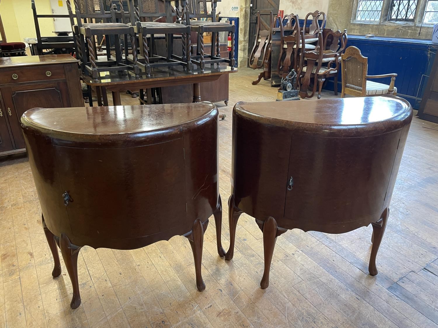 A pair of 1920s walnut bow front cupboards, with single cupboard doors, 85 cm wide