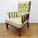 An early 20th century walnut framed button back armchair, with a padded back, arms and seat, on