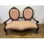 A mahogany double seat, with carved back rails, padded back, arms and seat, 120 cm wide