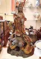 A Chinese carving of a deity, standing above a dragon, 70 cm high