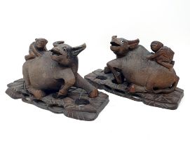 A pair of Chinese carvings of oxen, with figures on their backs, 30 cm wide (2)