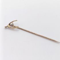 A late 19th/early 20th century yellow metal and diamond stick pin, in the form of a wishbone