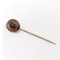 A late 19th/early 20th century yellow coloured metal, red stone and red enamel stick pin Provenance: