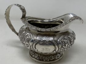 A George III silver cream jug, crested, with embossed decoration, 8.70 ozt