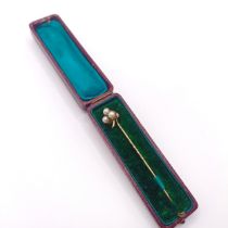 A late 19th/early 20th century yellow metal and cultured pearl stick pin, in a vintage jewellery box