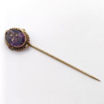 A late 19th/early 20th century yellow metal and engraved purple stone stick pin Provenance: From a