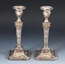 A pair of Edwardian silver candlesticks, decorated ribbon ties, bows and ram face masks, London