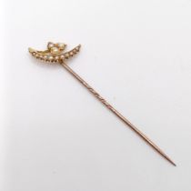 An early 20th century yellow metal and seed pearl stick pin, in the form of a leaf and a cresent
