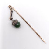 A late 19th/early 20th century yellow metal white stone and green stone stick pin, in the form of an
