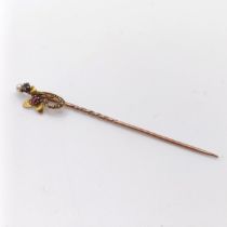 An early 20th century yellow coloured metal and multi-coloured stone stick pin, in the form of a