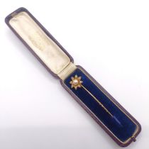 An early 20th century yellow metal and pearl stick pin, in the form of a flower, in a vintage