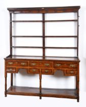 An 18th century oak dresser, with a three tier plate rack, on a base with seven drawers, above an
