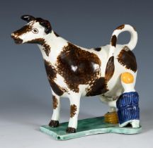 A 19th century creamware creamer, in the form of a cow being milked, possibly Yorkshire, 15 cm