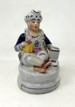 A Staffordshire quill holder, in the form of a street seller, 12 cm high