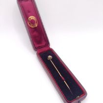 A diamond and yellow metal stick pin, in a vintage jewellery box