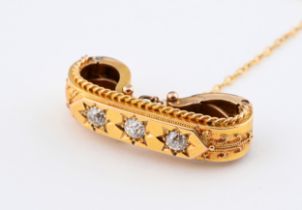 A yellow coloured metal and three stone diamond brooch, with a clip back type setting, and a