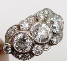 A platinum and diamond ring, with three diamonds, within a surround of further diamonds in a