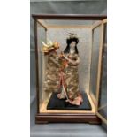A vintage japanese porcelain Geisha Girl doll, dancing with her husbands samurai helmet, adorned