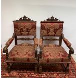 A pair of antique carved arm chairs with oak leaf design, upholstered with burgundy damask