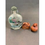 An oriental glass bottle with two carved netsukes