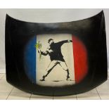 A stencil painting of Banky’s The Flower Thrower sprayed onto a 1991-1997 mark 1 Peugeot car