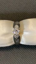 A white gold ring set with 3 diamonds and 2 diamond baguette shoulders, central diamond 0.35
