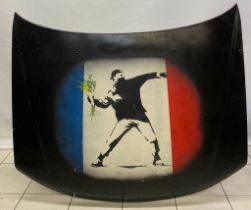 A stencil painting of Banksyâ€™s The Flower Thrower sprayed onto a 1991-1997 mark 1 Peugeot car