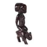 African / Tribal Art. A Congo luba figure depicting a female figure riding on the back of an