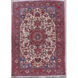 A Persian Isfahan woven rug with central medallion on a red floral ground, 148 by 102cms.