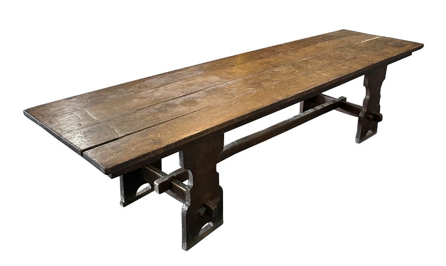 A large 17th century style oak refectory table with four plank top, on trestle supports joined by