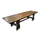 A large 17th century style oak refectory table with four plank top, on trestle supports joined by